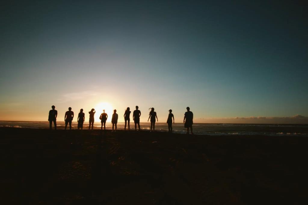 People standing on a beach facing the water